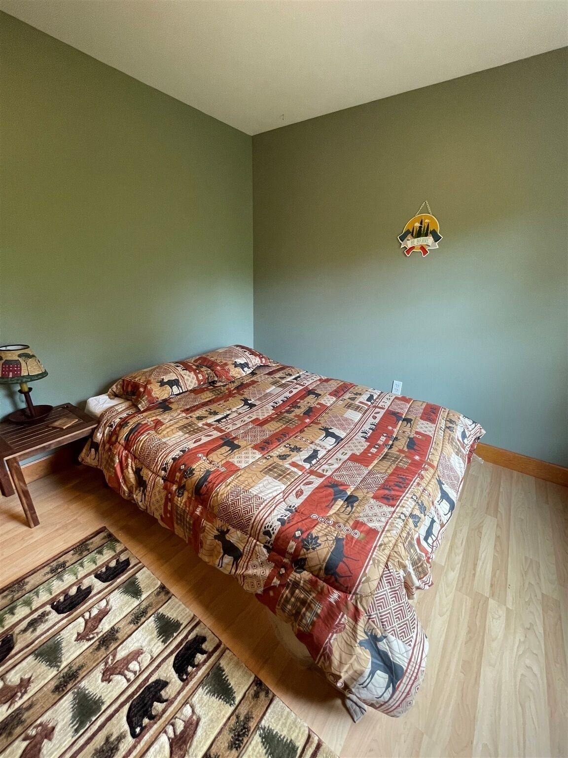 Une chambre à coucher avec un grand lit, une table de chevet en bois, un tapis à motifs et un luminaire fixé au mur.