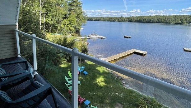 A balcony with a view of a lake, dock, and greenery. - Tremont Limit 10 4 Bedroom Villa by RedAwning (Bridgton)