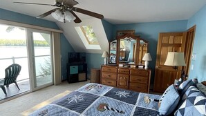 A bedroom with a large bed, a ceiling fan, a dresser, a mirror, and a view of the outdoors through a sliding glass door. - Tremont Limit 10 4 Bedroom Villa by RedAwning (Bridgton)