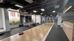 A gym with exercise equipment, a wooden floor, and a reception desk. - Supertramp House - Gold View Apartment (Ho Chi Minh City)
