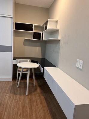 Une petite pièce moderne avec une table et une chaise blanches, des étagères intégrées et un banc le long du mur.