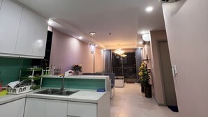 A modern kitchen with white cabinets, a built-in sink, and a dining area with a table and chairs. - Supertramp House - Gold View Apartment (Ho Chi Minh City)