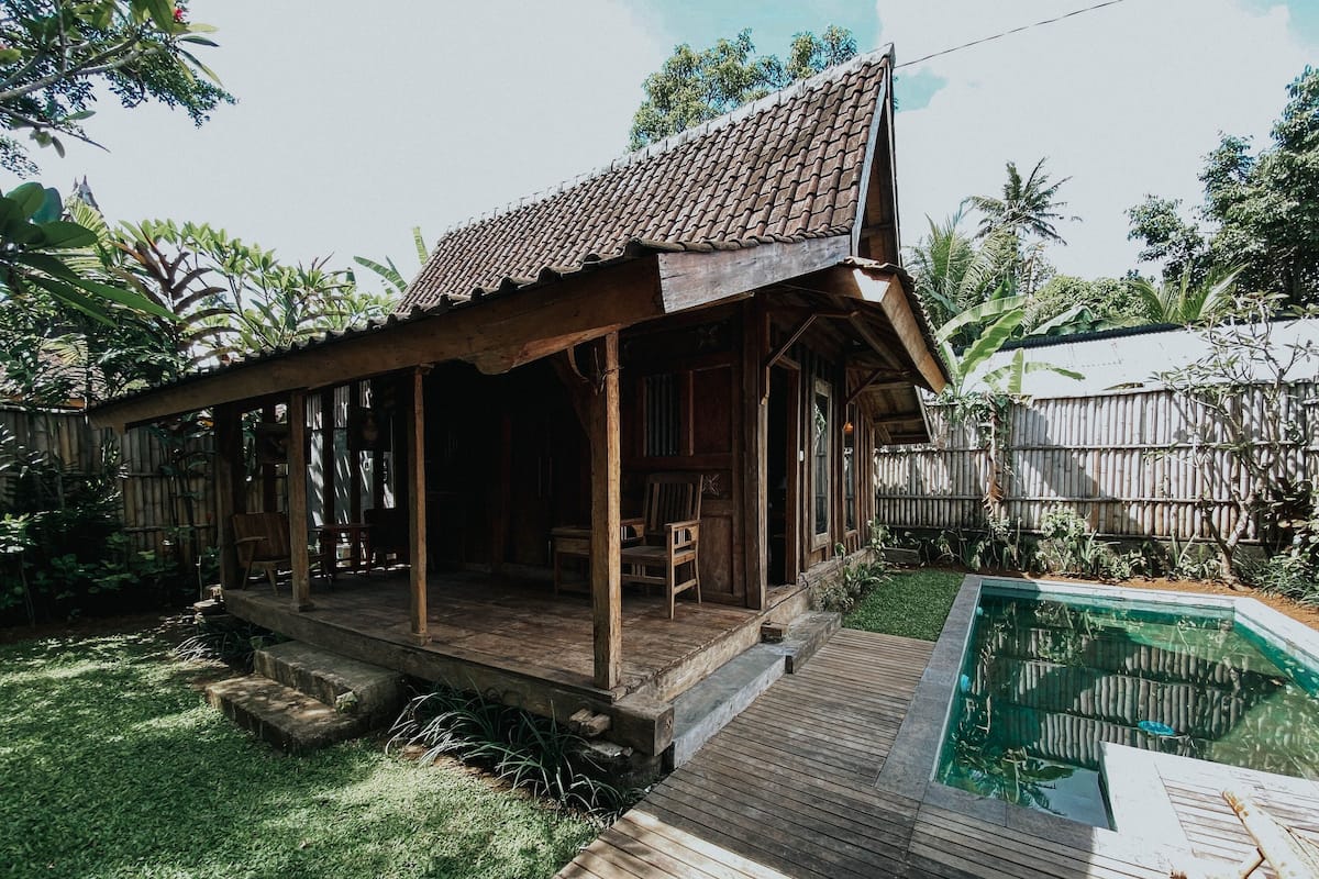 Une maison en bois avec un toit en tuiles, une terrasse en bois et une piscine.