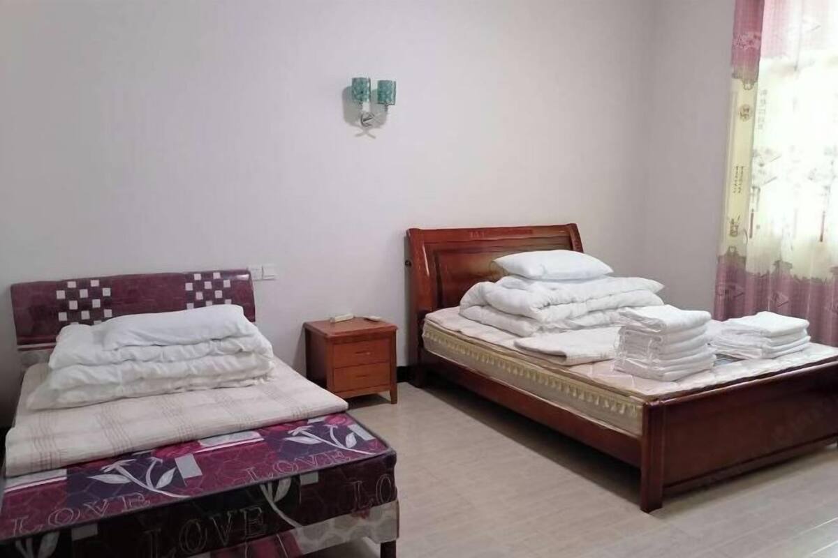 A bedroom with two beds, a nightstand, and a wall-mounted light fixture.