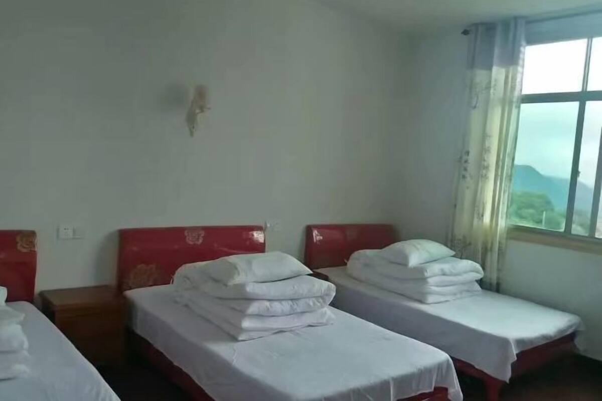 A hotel room with two single beds, each with white bedding and red headboards.