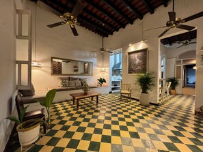 A spacious living area with a checkered floor, ceiling fans, a sofa, a coffee table, and potted plants. - La casa de Madamme Cocotte (Santa Marta)