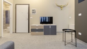 Ein modernes Hotelzimmer mit Fernseher, einem Schrank, einer Stierkopf-Dekoration und einem kleinen Tisch.