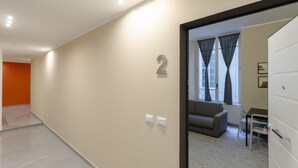 Eine moderne Wohnung mit neutraler Farbgestaltung, einem Sofa, einem Esstisch und einem Kleiderschrank.