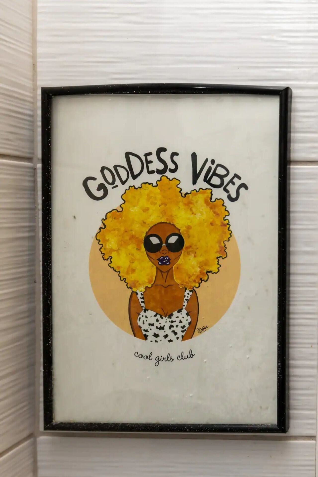 En indrammet kunsttryk med titlen 'Goddess Vibes', der viser en stiliseret illustration af en kvinde, og teksten 'cool girls club' forneden.