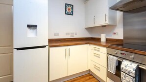 A modern kitchen with white cabinets, a stainless steel oven, and a water dispenser. - Cosy 1 Bedroom Flat in Shadwell (London)