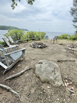 Un espace aménagé au bord du lac, avec des chaises en bois et un foyer.