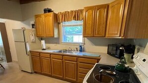 Une cuisine avec des meubles de rangement en bois, une cuisinière et un réfrigérateur.