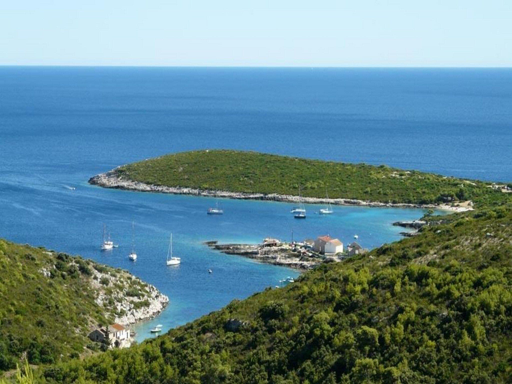 Un paysage côtier avec une petite île, des bateaux et quelques bâtiments.