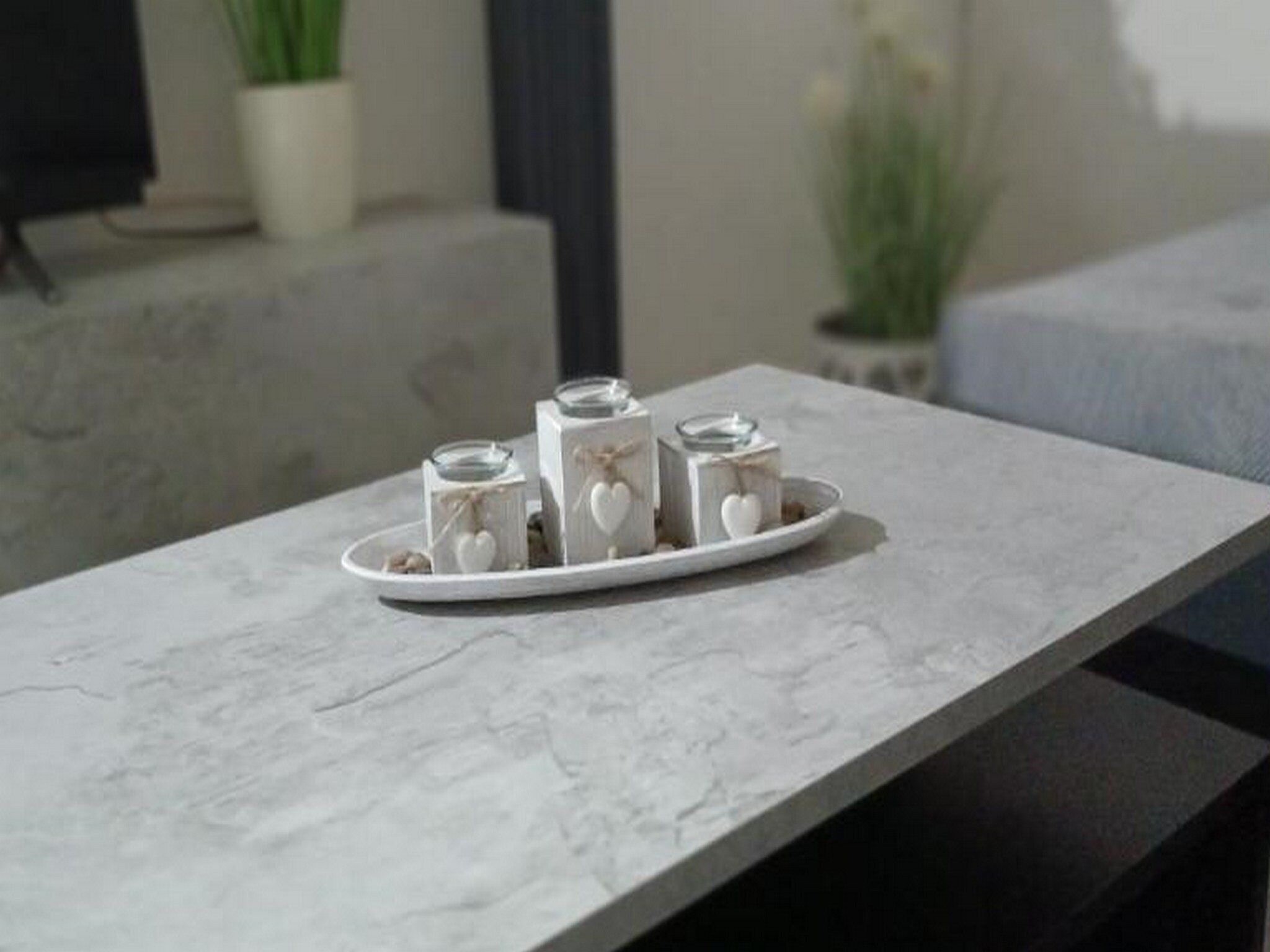 A marble table with a white tray holding three glass jars with heart-shaped decorations.