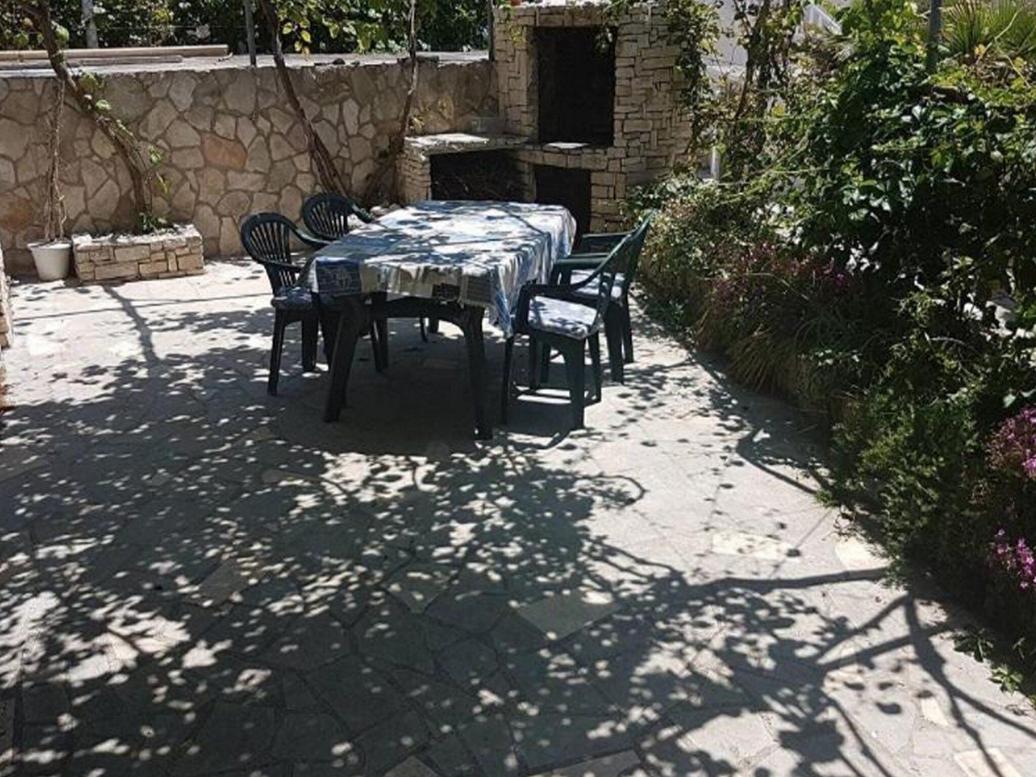 An outdoor patio with a stone wall, a table with chairs, and a brick oven.
