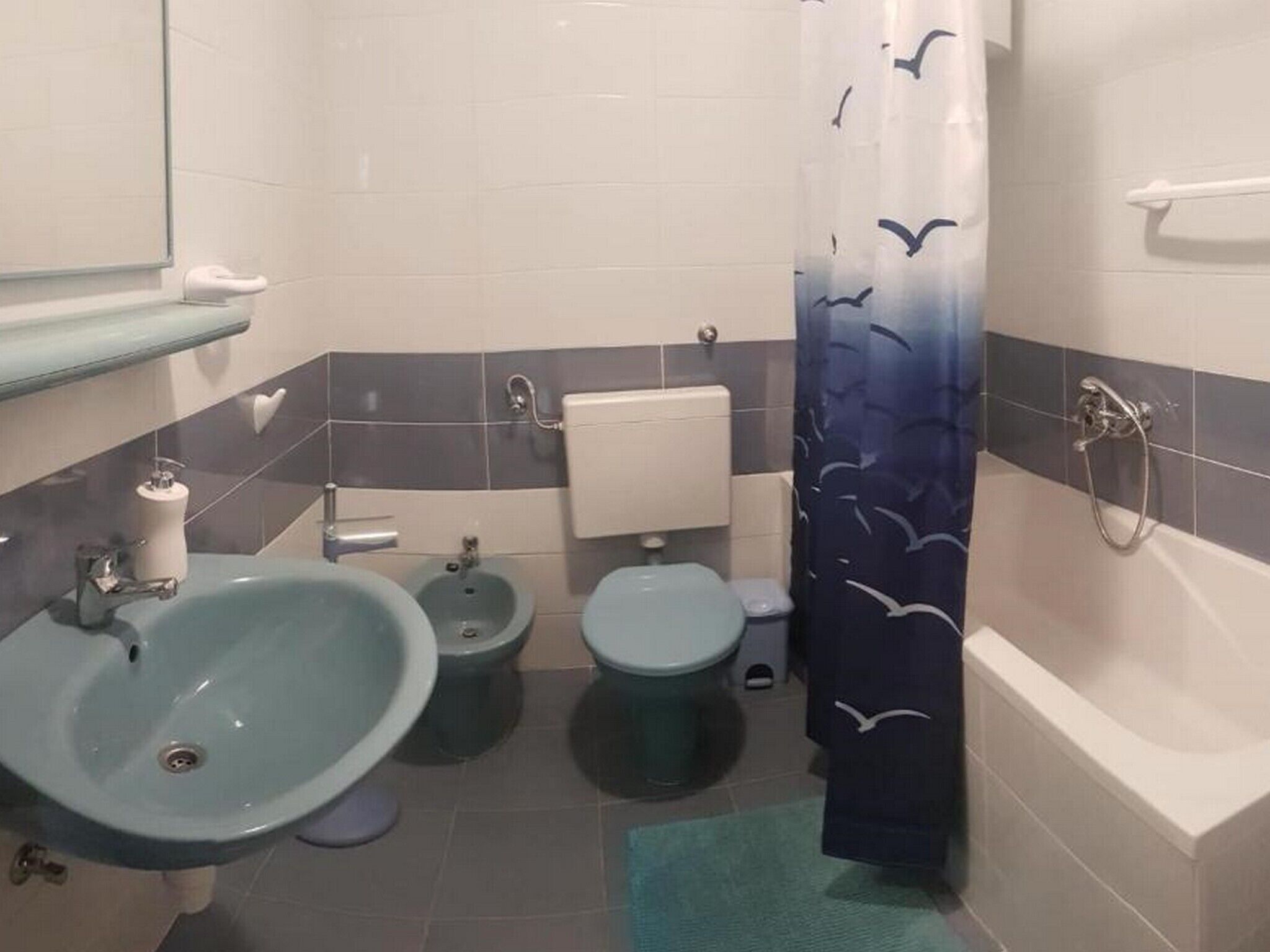 A bathroom with a sink, bidet, toilet, and bathtub.