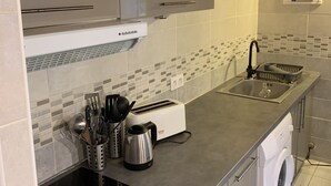 A modern kitchen with a built-in oven, a washing machine, and a sink. - Provencal Mazet 5 minutes from Isle sur la Sorgue - Private parking (Le Thor)