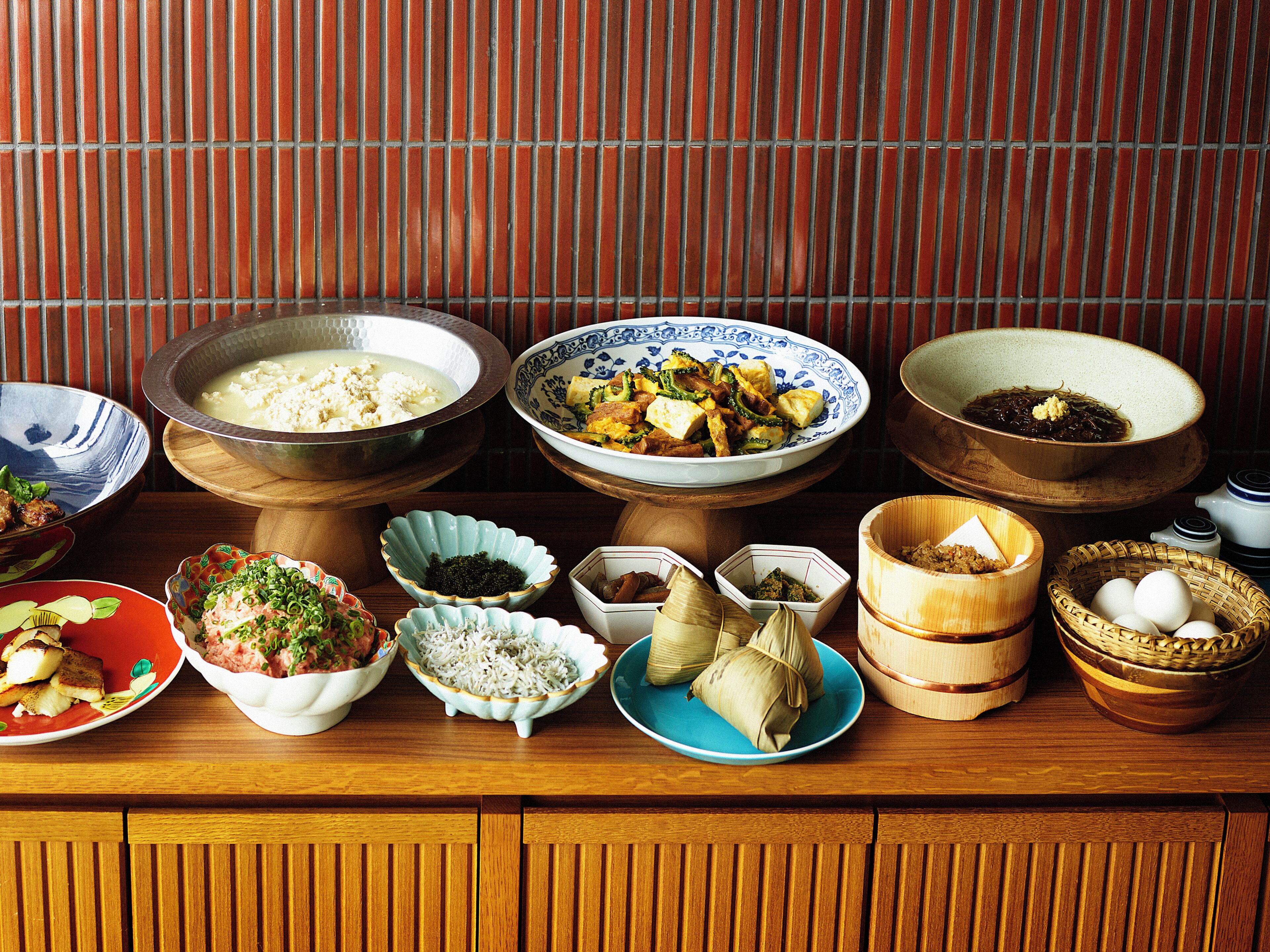 A variety of dishes arranged on a wooden table against a striped wall.