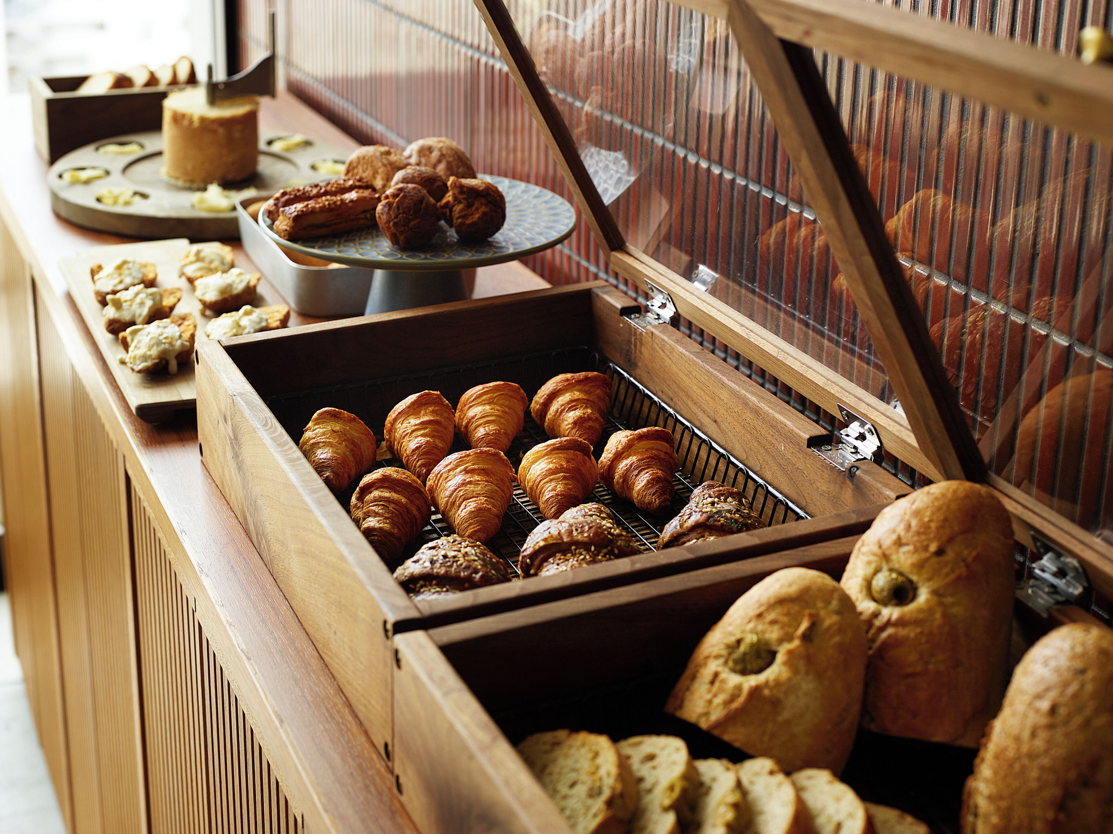 Een bakkerijvitrine met croissants, brood en gebak.