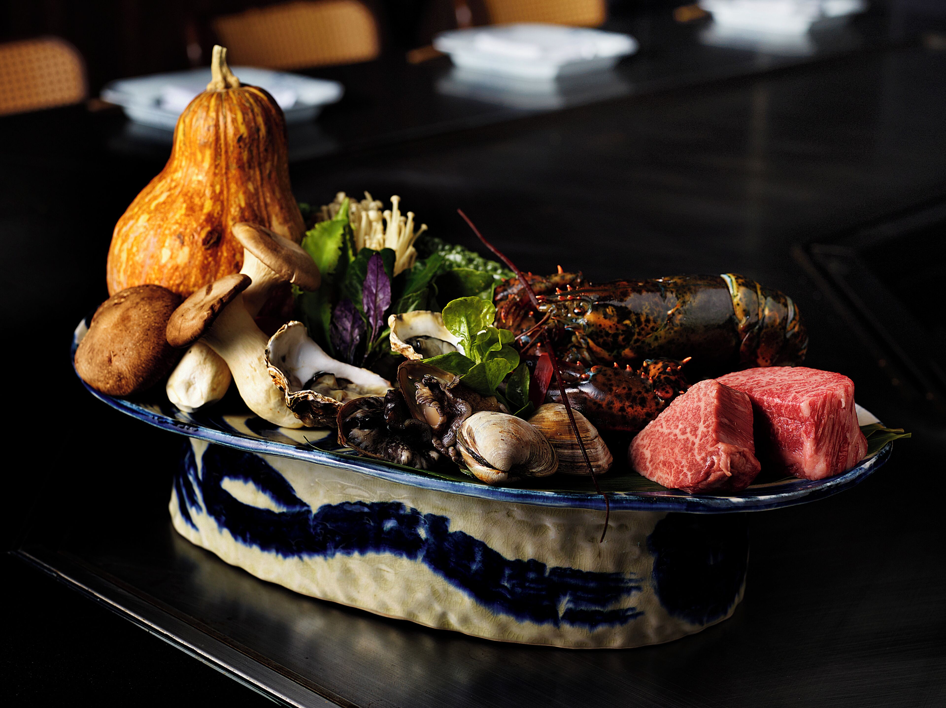 A table with a variety of food items including a pumpkin, mushrooms, clams, and a piece of meat.