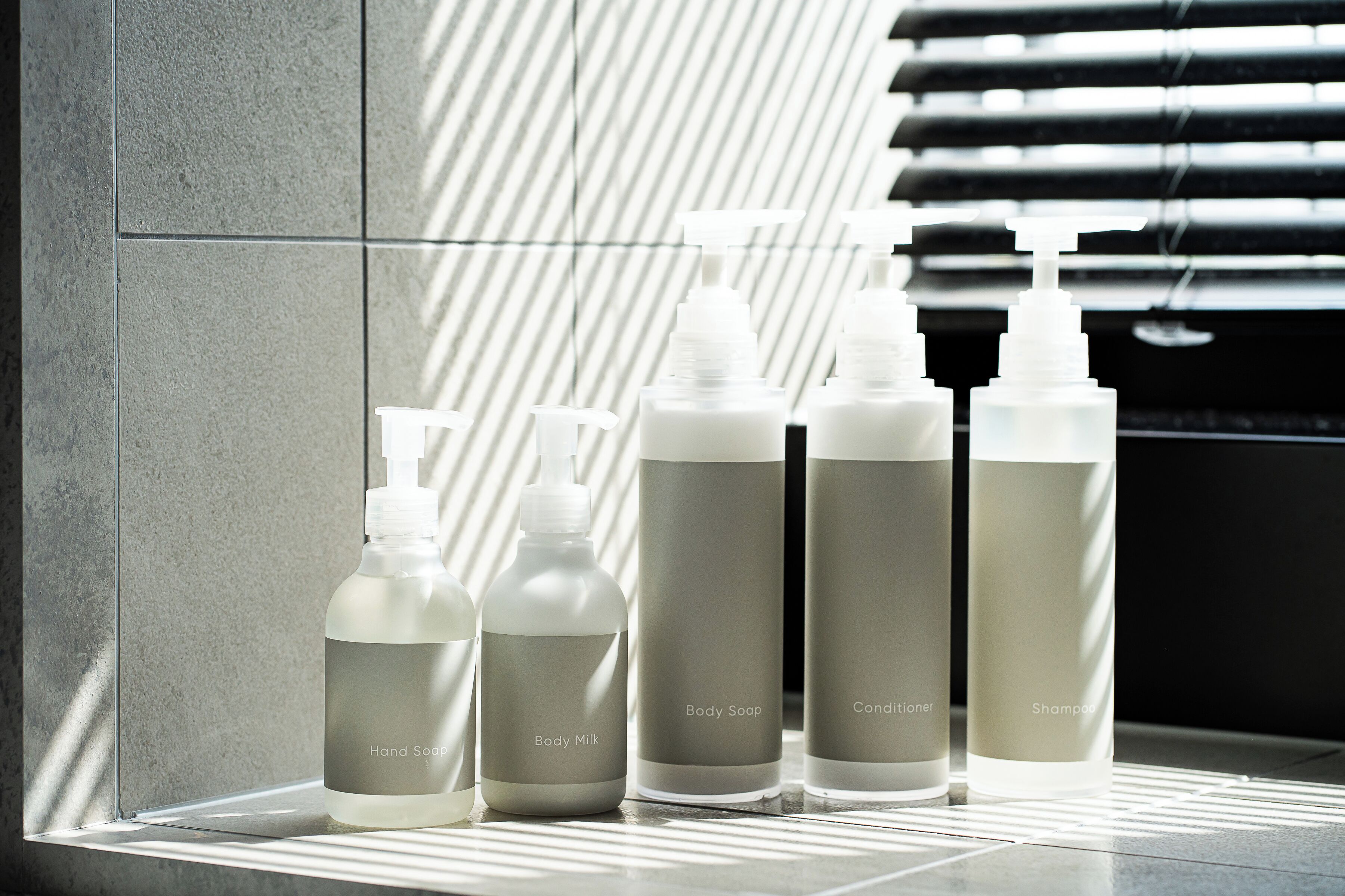 A row of five bottles of personal care products on a ledge.