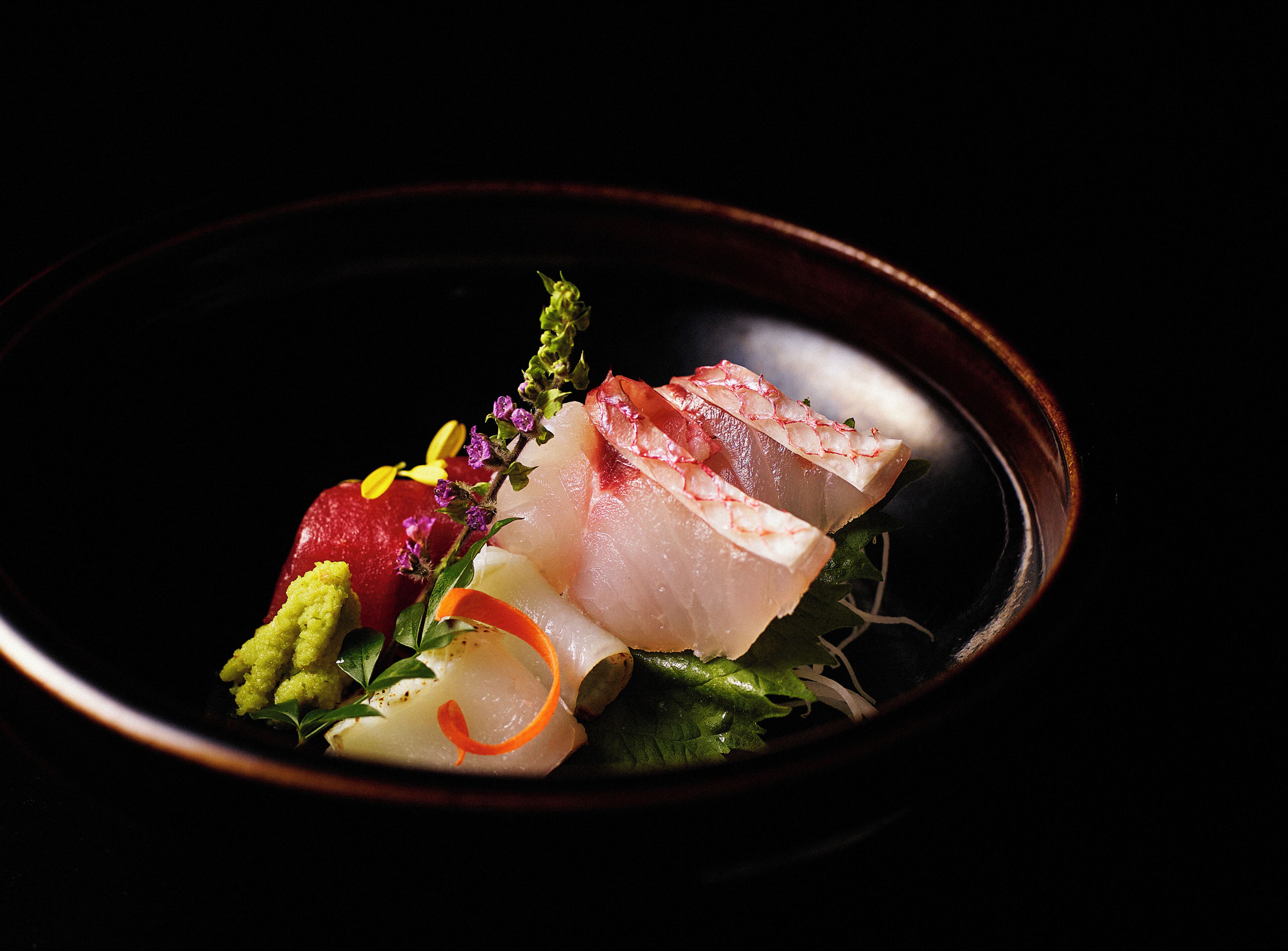 A plate of sashimi with various garnishes.