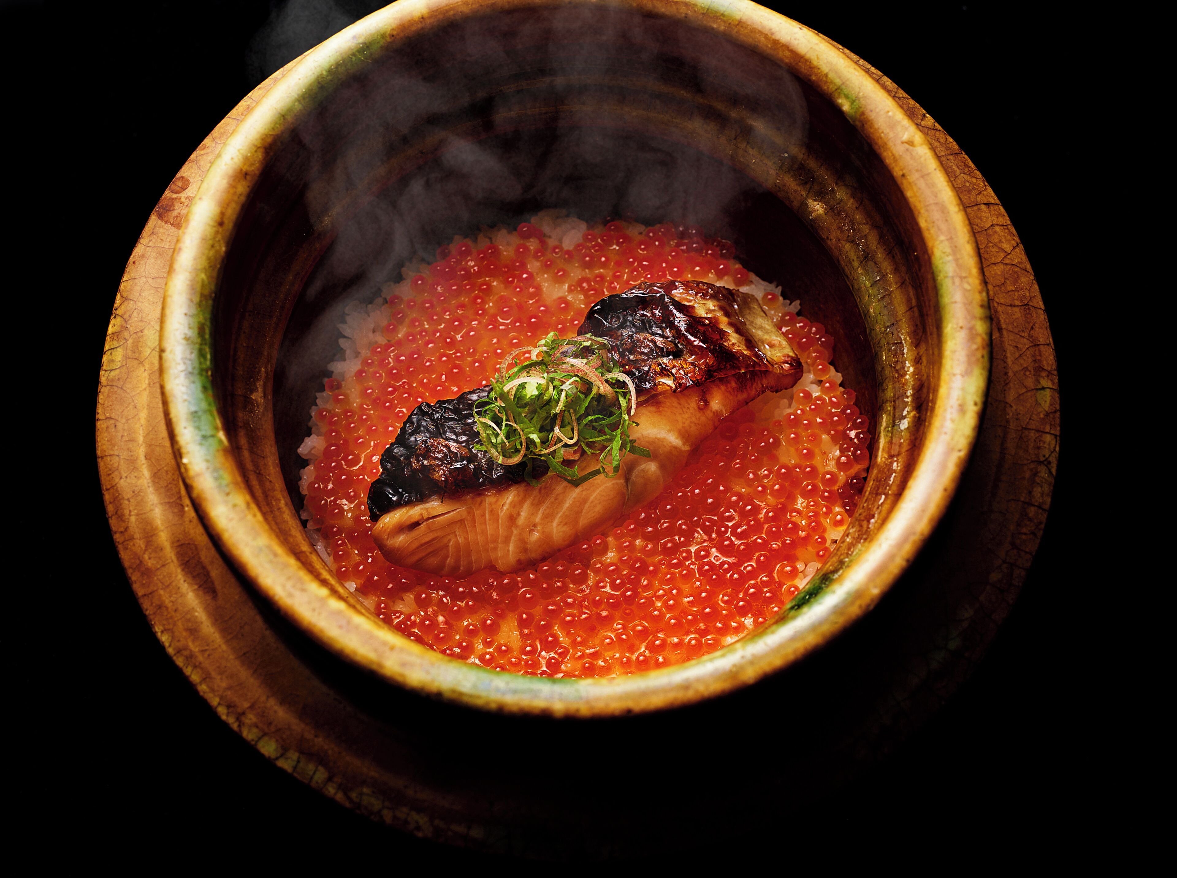 A bowl of food with a fish and red caviar.
