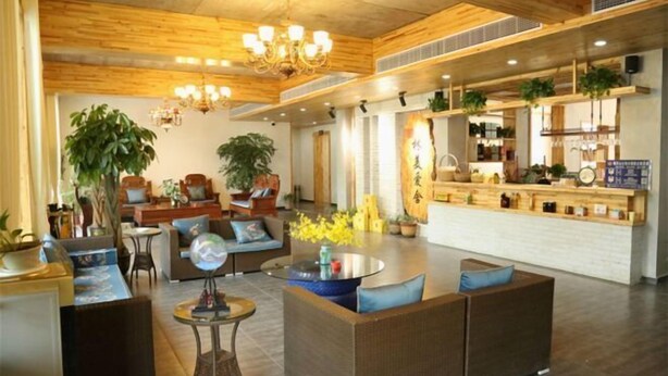 A modern hotel lobby with wooden ceiling beams, a central seating area with sofas and a coffee table, and a bar area with plants and kitchen items. - Yichun Jingfu Courtyard · Linmei Aishe Homestay (Yichun)