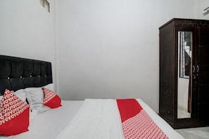 A neatly made bed with white and red bedding, a dark headboard, and a wardrobe with a mirror. - Hotel O Dinda Homestay Syariah (Dumai)