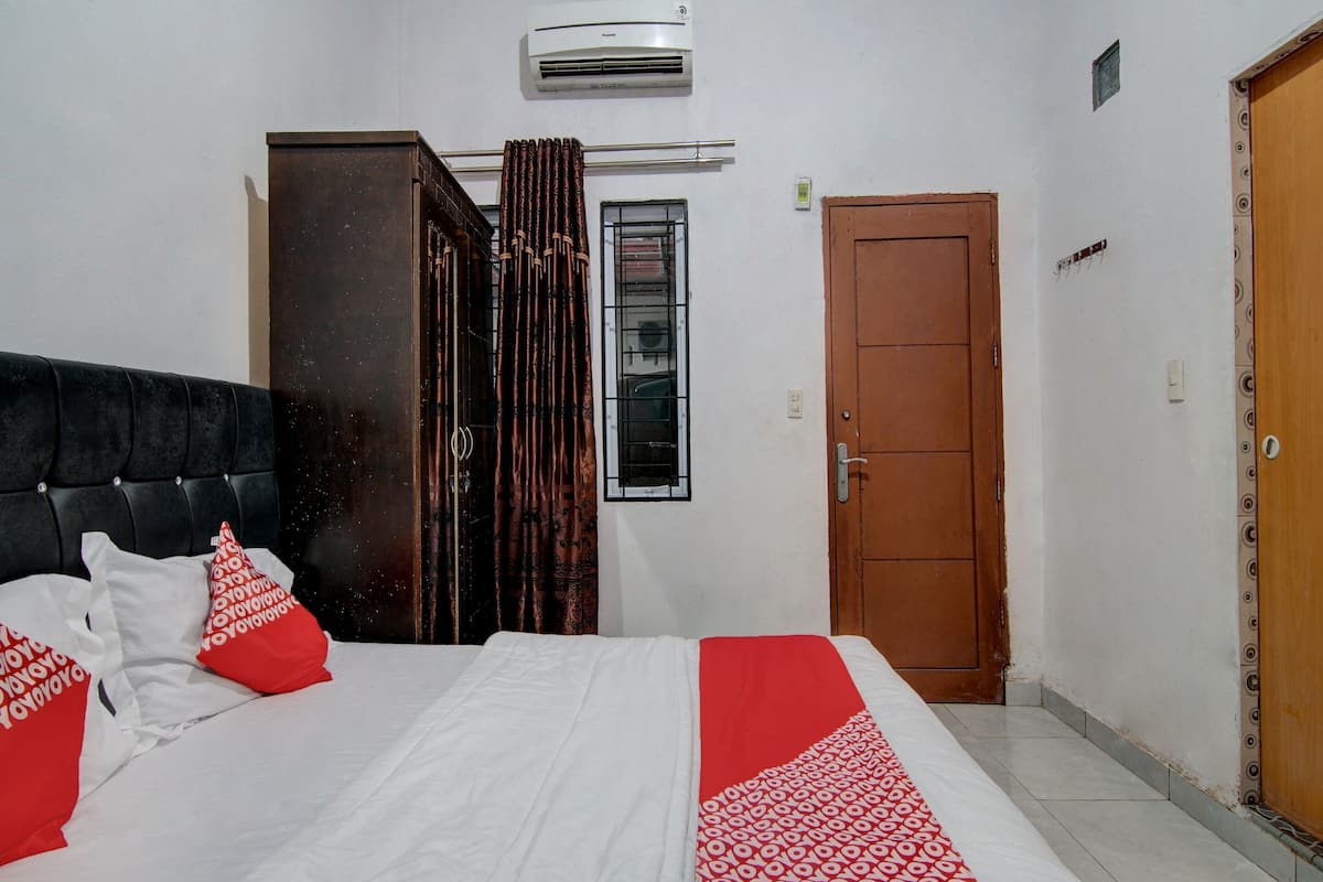 Une chambre à coucher avec un lit, une fenêtre avec des rideaux, un climatiseur et une porte.