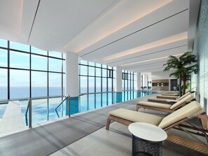 A modern indoor pool area with lounge chairs and a view of the ocean. - MATIE Osiria (Busan)