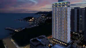 A high-rise hotel with multiple floors, a prominent entrance, and a view of the coastline.