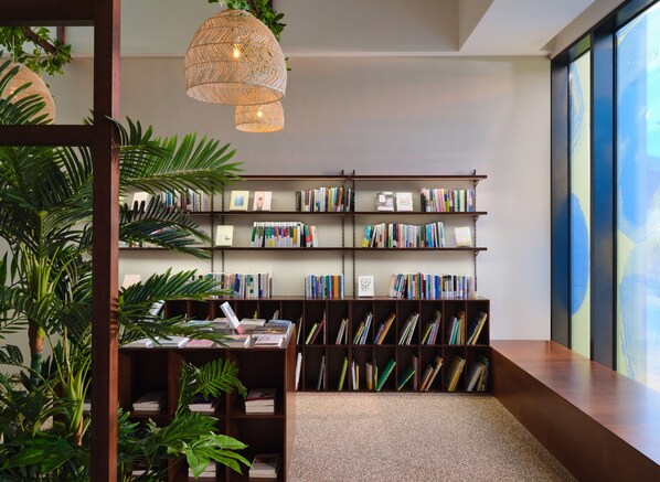 A modern library with bookshelves, a hanging light fixture, and indoor plants. - MATIE Osiria (Busan)