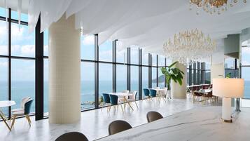 Ein geräumiges Zimmer mit großen Fenstern, einer Kristallleuchter und Blick auf das Meer.