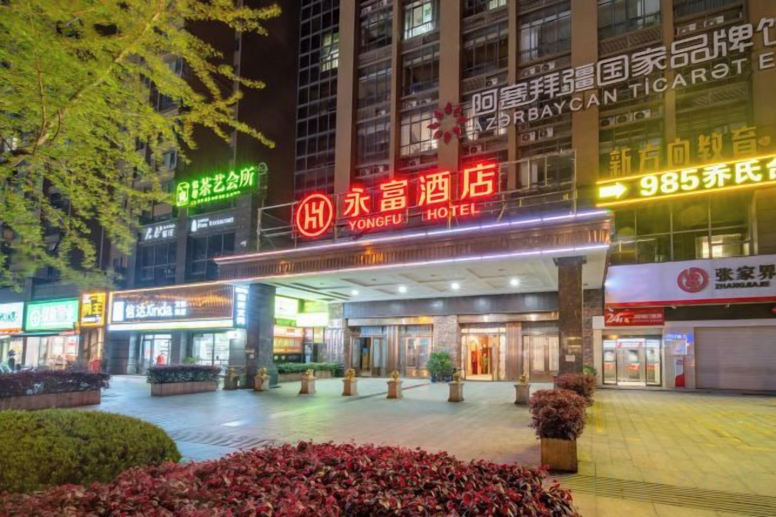 A hotel entrance with a large sign, a covered entrance area, and surrounding greenery.