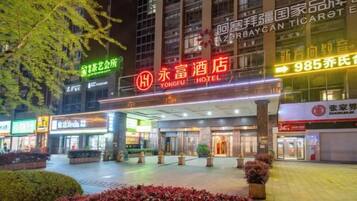 A hotel entrance with a large sign, a covered entrance area, and surrounding greenery.