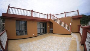 Un edificio con un balcón curvo, una escalera y una puerta de cristal.