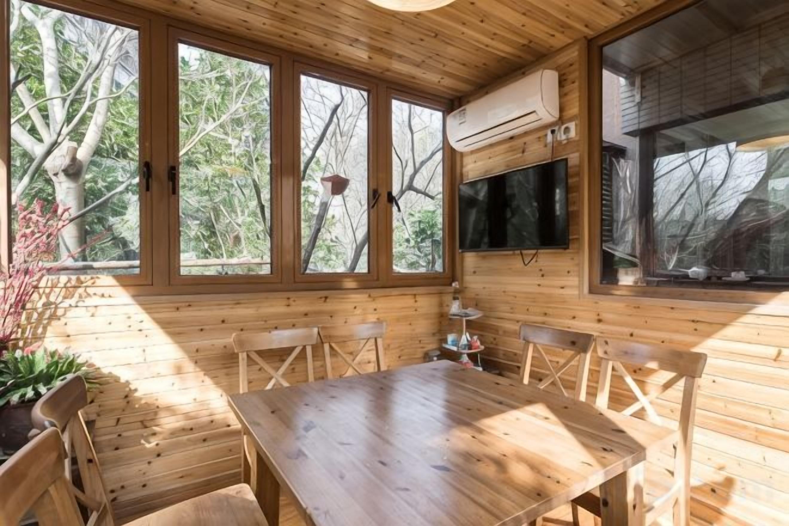 Un intérieur en bois avec une table à manger, des chaises et de grandes fenêtres.