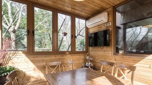 A wooden cabin with a dining table, chairs, and large windows. - Shenmi Sidou Hostel (Nanjing)