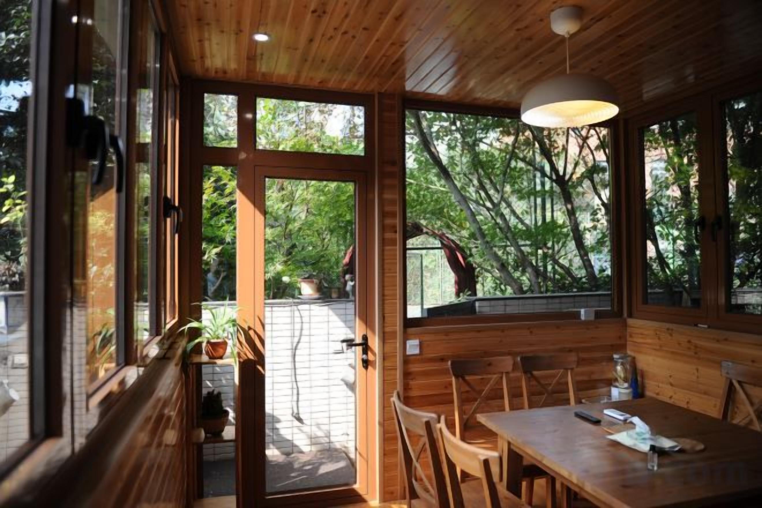 Un interior de madera con un comedor, ventanas amplias y vistas al exterior.