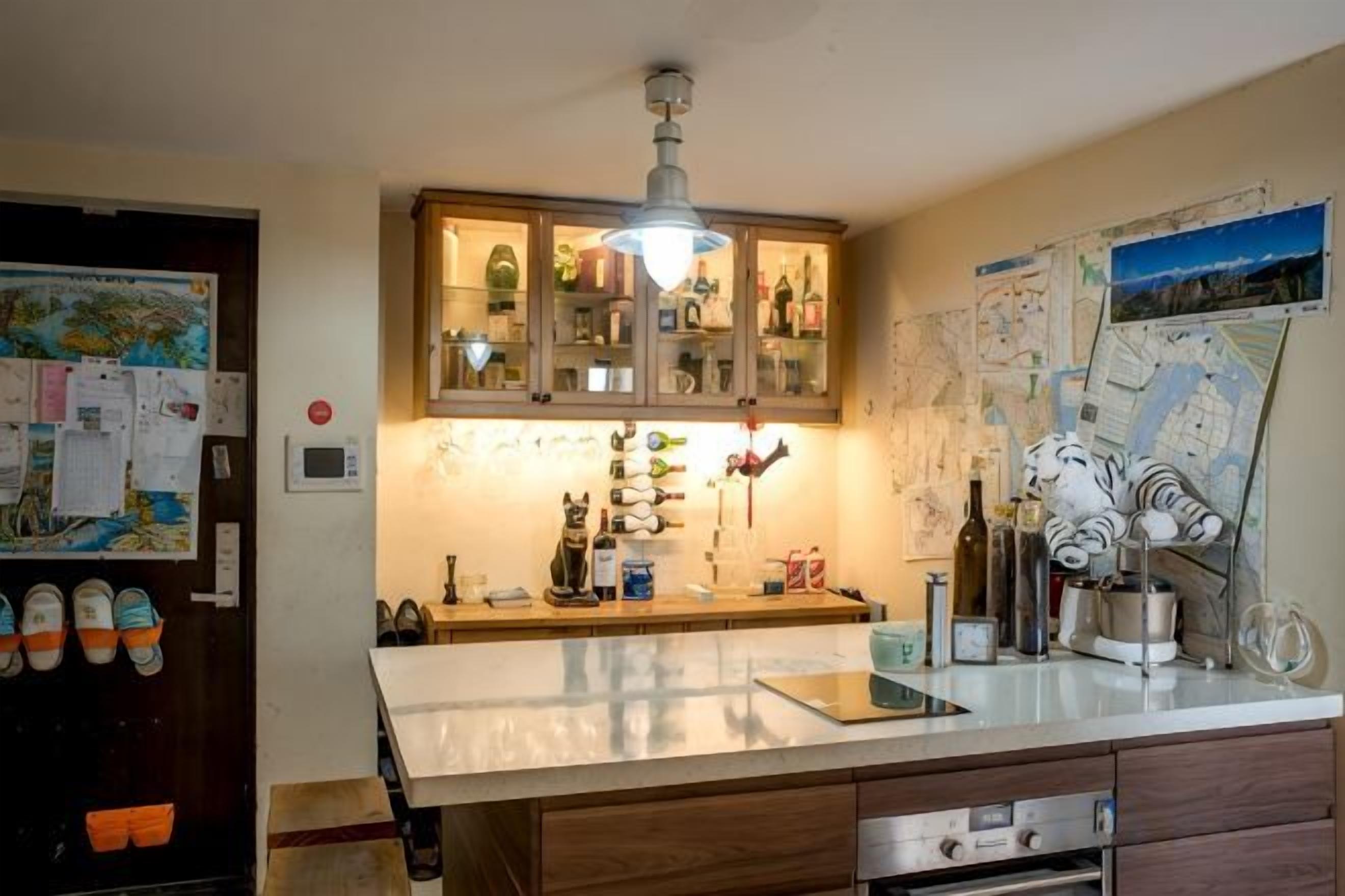 Cozinha com armário de madeira, bancada e luminária suspensa.