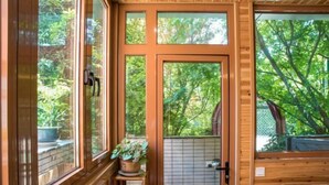 A wooden cabin with large windows, a door, and a small table with a plant. - Shenmi Sidou Hostel (Nanjing)