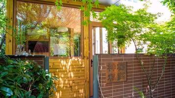 A wooden gate leading to a building with a brick wall and a sign with Japanese characters.