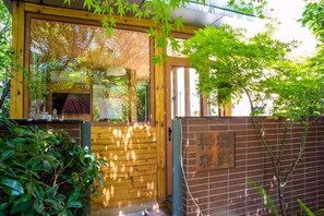 Una verja de madera que da a un edificio con un muro de ladrillo y un cartel con caracteres japoneses.