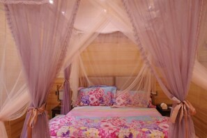 A bed with a floral bedspread, a canopy, and a wooden headboard.