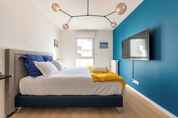 A bedroom with a bed, a TV, and a unique ceiling light fixture.
