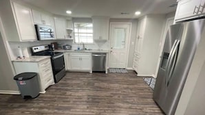 A kitchen with white cabinets, a stainless steel refrigerator, a dishwasher, and a stove.