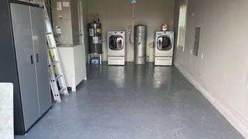 Una lavandería con cuatro lavadoras y secadoras, un calentador de agua y un refrigerador.