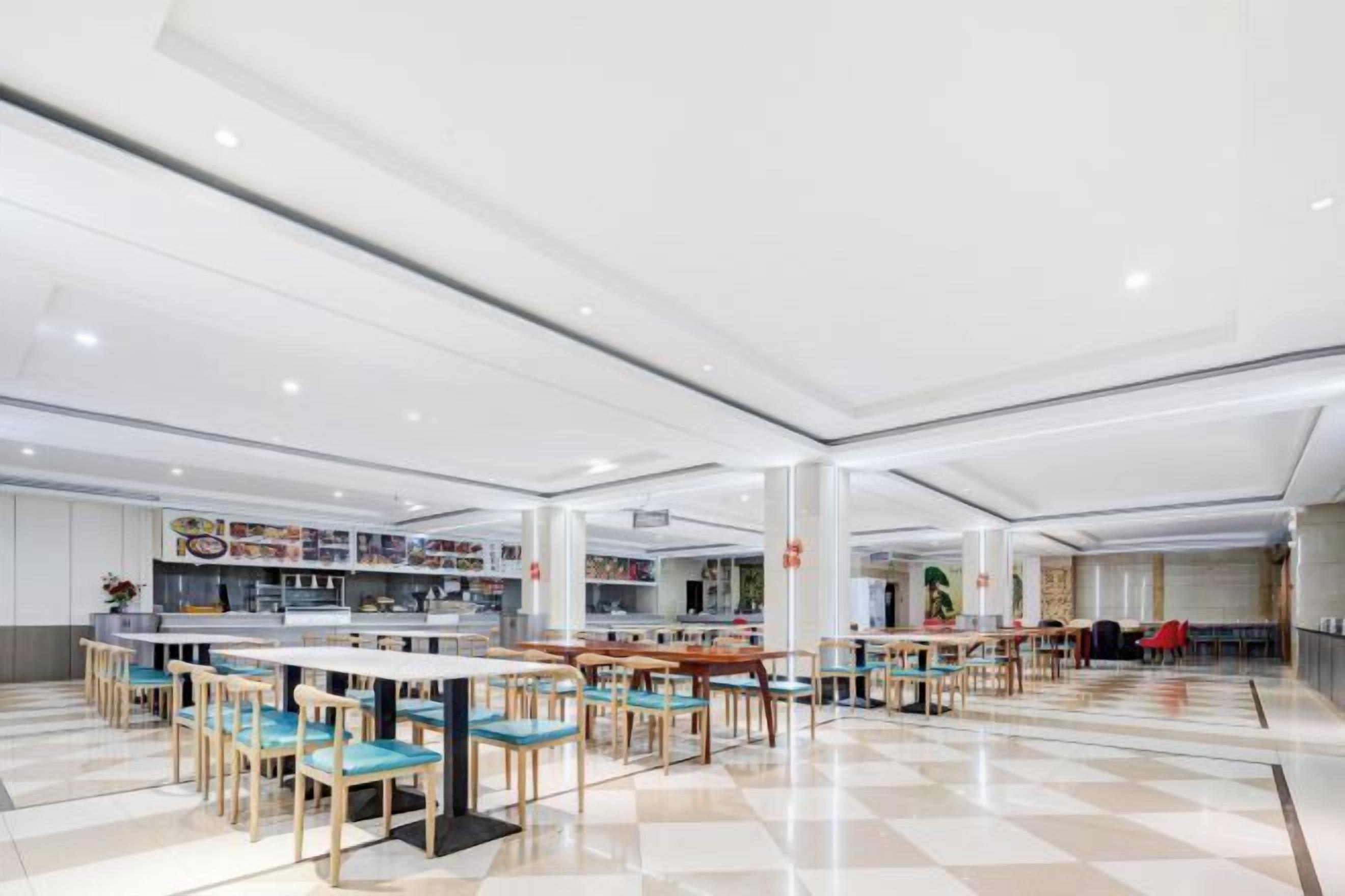 A spacious indoor dining area with multiple tables and chairs, a central counter, and a tiled floor.