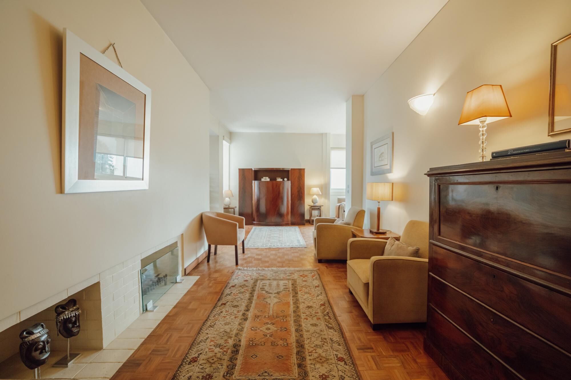 A spacious living room with a fireplace, a wooden cabinet, and a large rug.